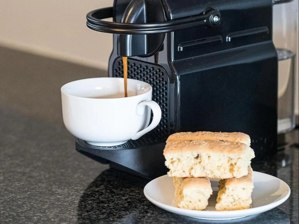 Espresso machine brewing coffee with scones and pastries on plate