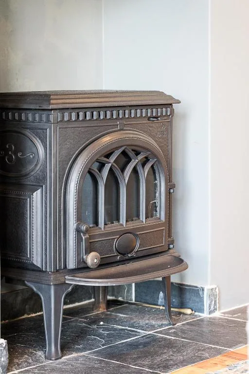 Ornate vintage wood-burning stove with arched glass door and decorative details