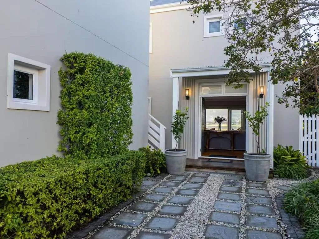Modern villa entrance with manicured hedges and paved courtyard