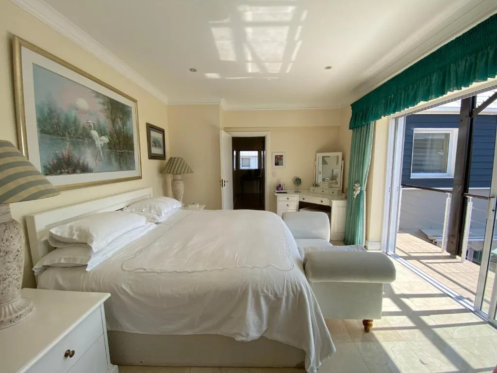 Bright bedroom with queen bed, vanity desk, and deck access doors