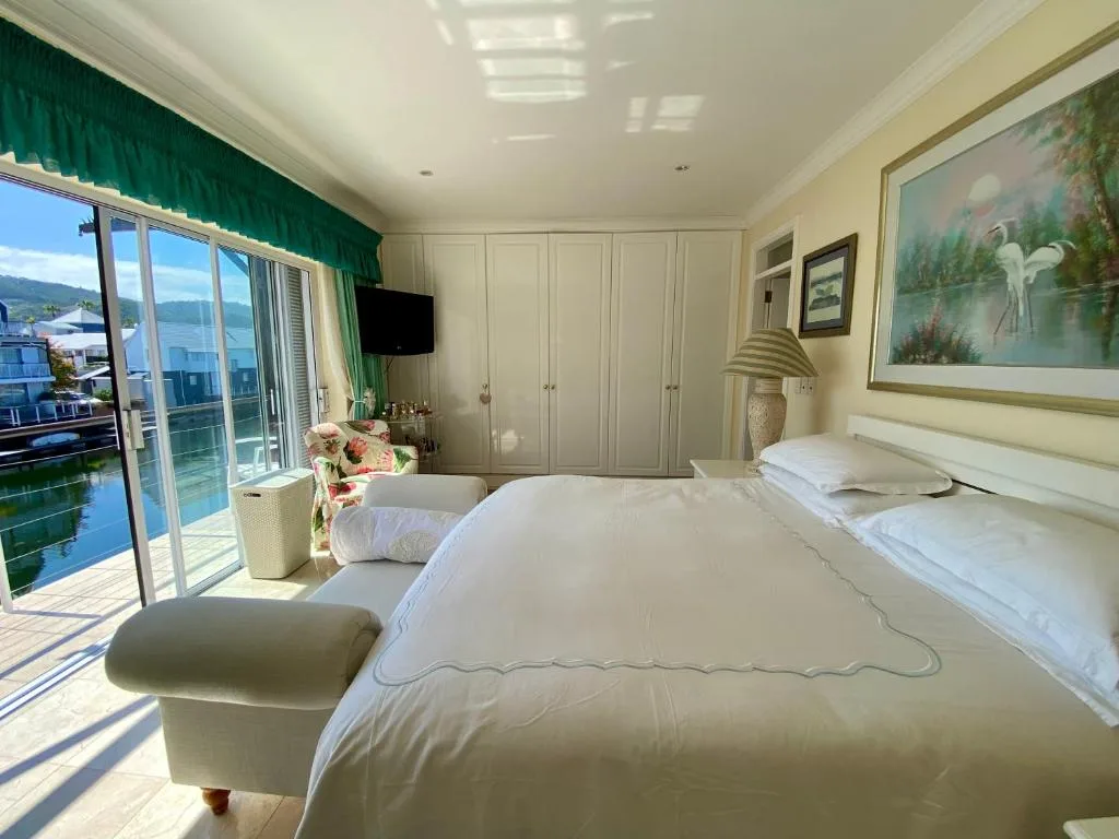 Spacious bedroom with double bed, water views, and lagoon access through glass doors