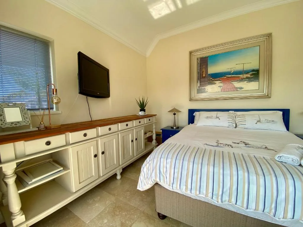 Bright bedroom with queen bed, blue headboard, and cream furnishings