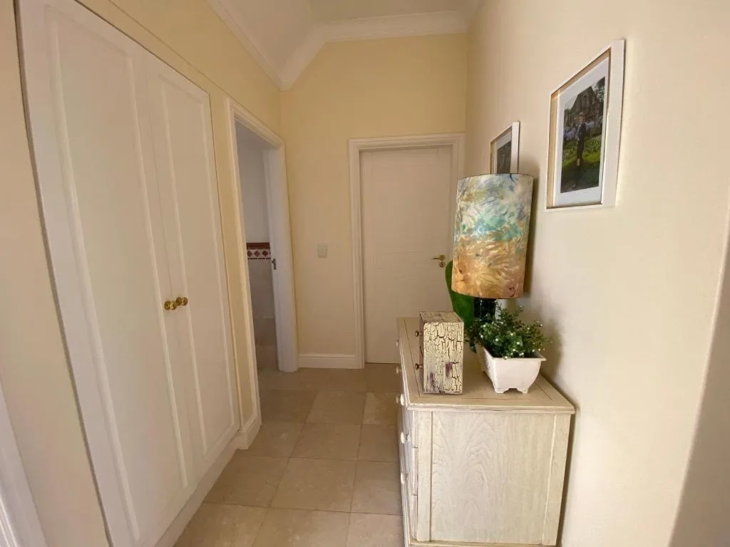 Hallway with cream walls, white doors, and decorative shelf with plant artwork