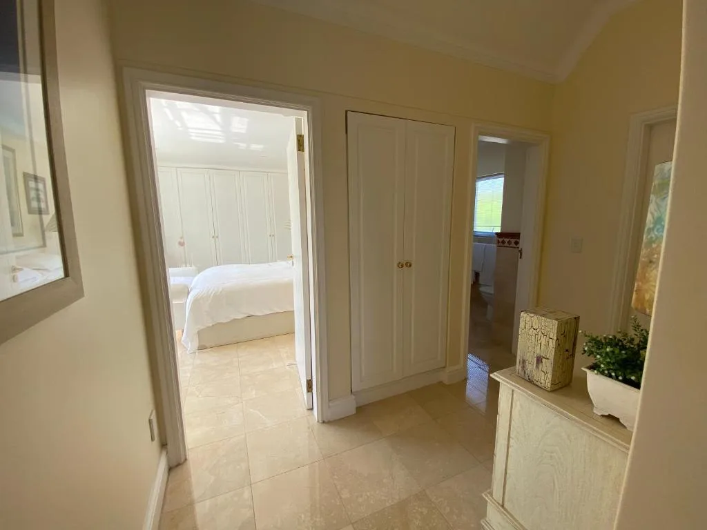 Light hallway with cream walls, tiled flooring, wardrobe doors, and bedroom access