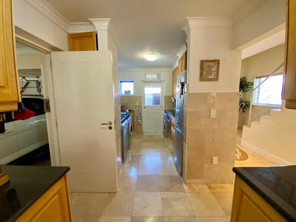 Bright galley kitchen with wooden cabinetry and stainless steel appliances