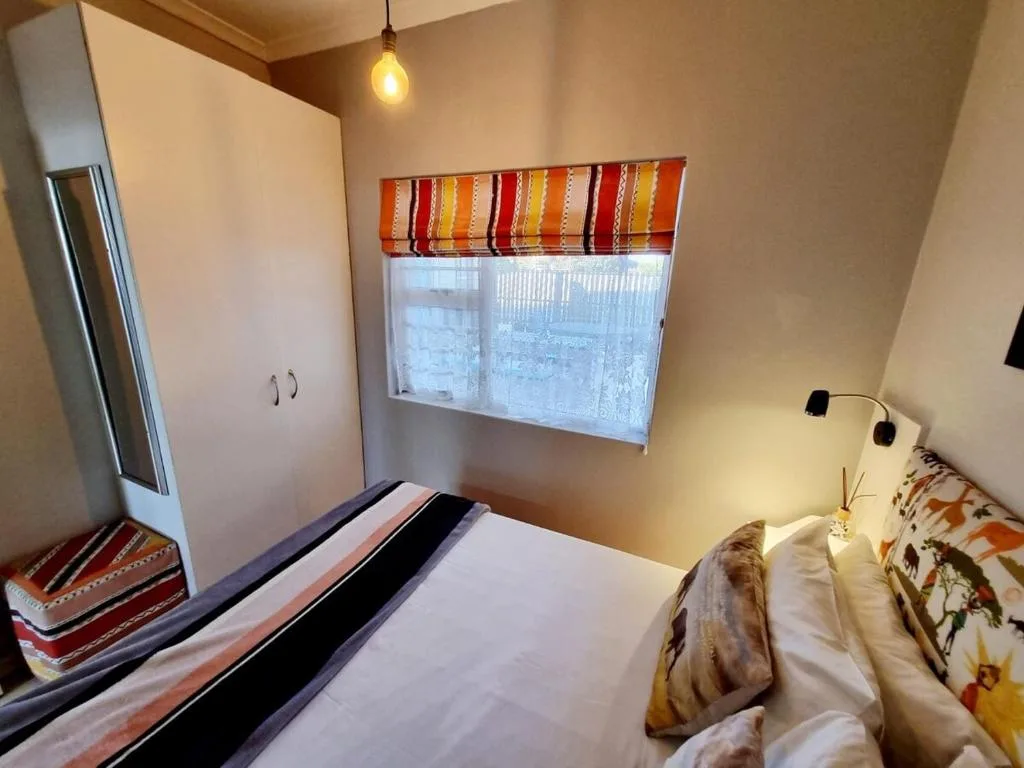 Cozy bedroom with double bed, wardrobe, and window with striped valance