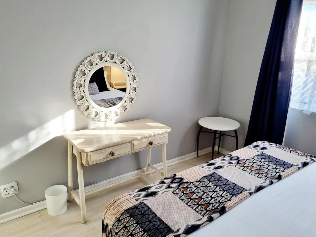 Bright bedroom with twin beds, ornate mirror, and cream vanity desk