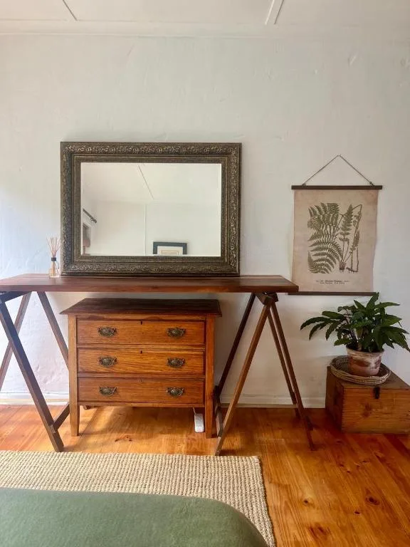 Wooden dresser with ornate mirror and botanical wall art decor