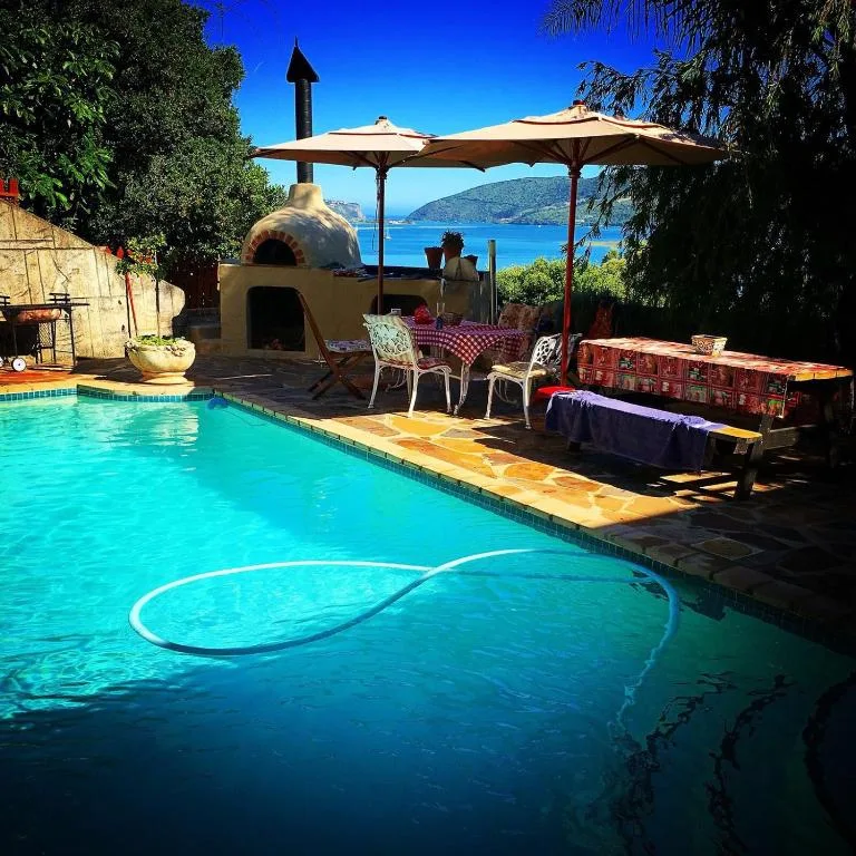 Swimming pool with mountain and ocean views, shaded dining area nearby