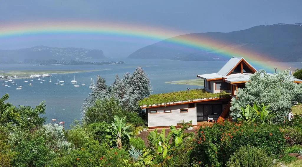 Scenic lagoon view with rainbow, moored boats, and surrounding mountains