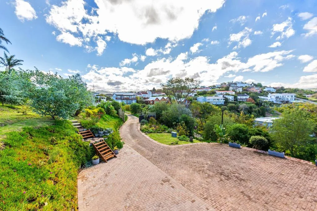 Scenic valley vista with manicured gardens, winding driveway, and town landscape below