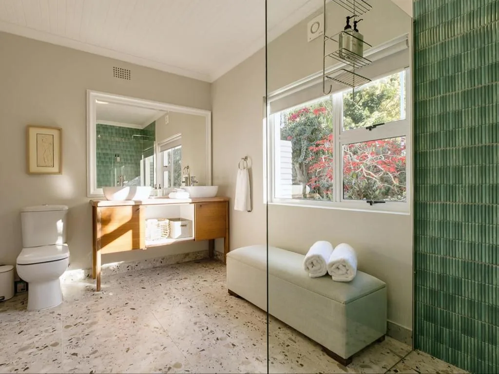 Modern bathroom with wooden vanity, walk-in shower, and garden views