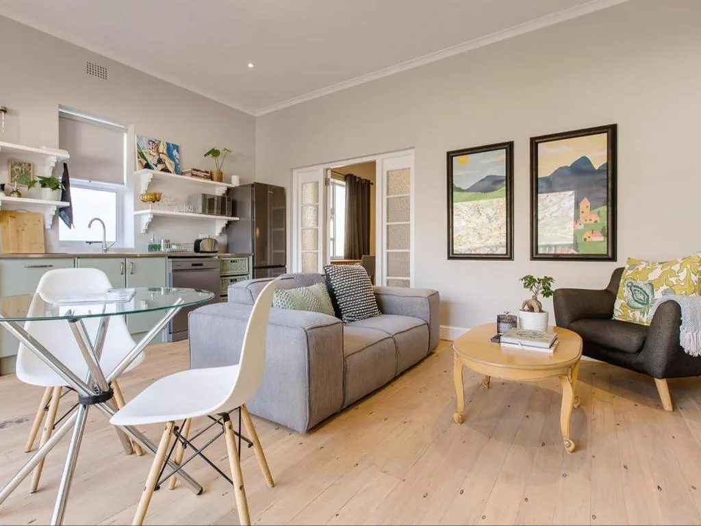 Open-plan living area with gray sofa, dining table, and kitchen in background