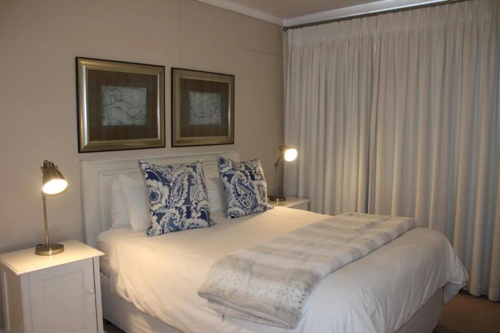 Bright bedroom with white bed, blue patterned pillows, framed artwork