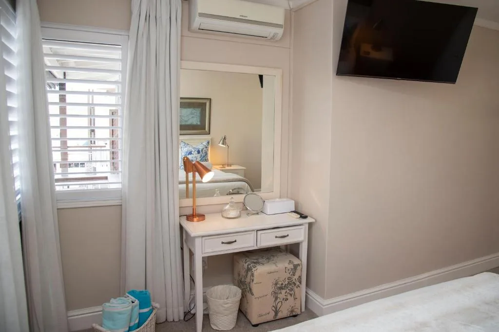 Bedroom with vanity desk, mirror, and window with shutters overlooking town