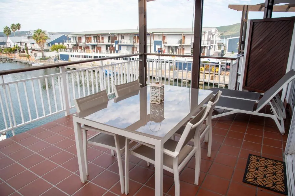 Waterfront balcony with dining table overlooking Knysna Heads and harbor