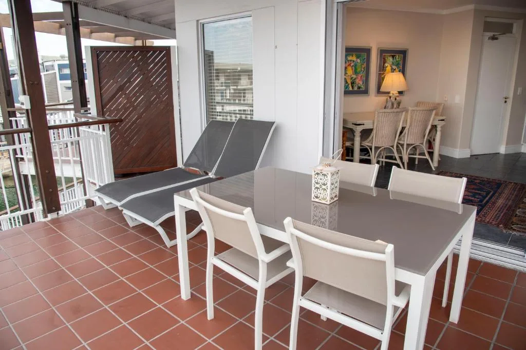Outdoor patio with dining table, loungers, and partial view of lounge area