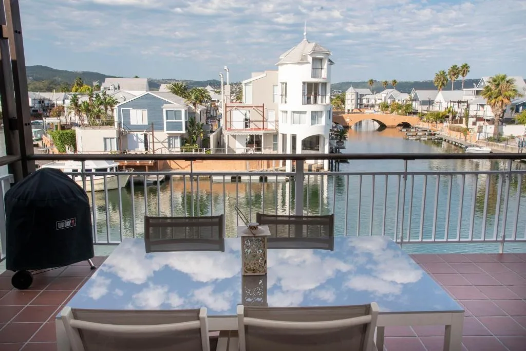 Waterfront deck with dining table overlooking Knysna lagoon and houses