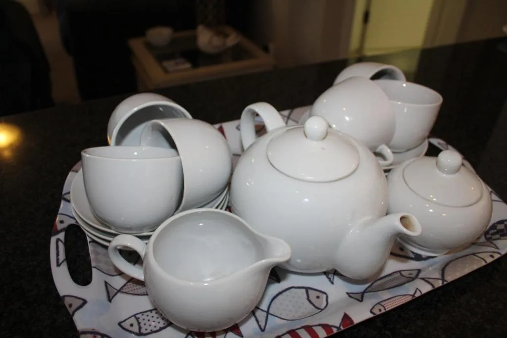 White ceramic tea service set with teapots, cups, and saucers displayed