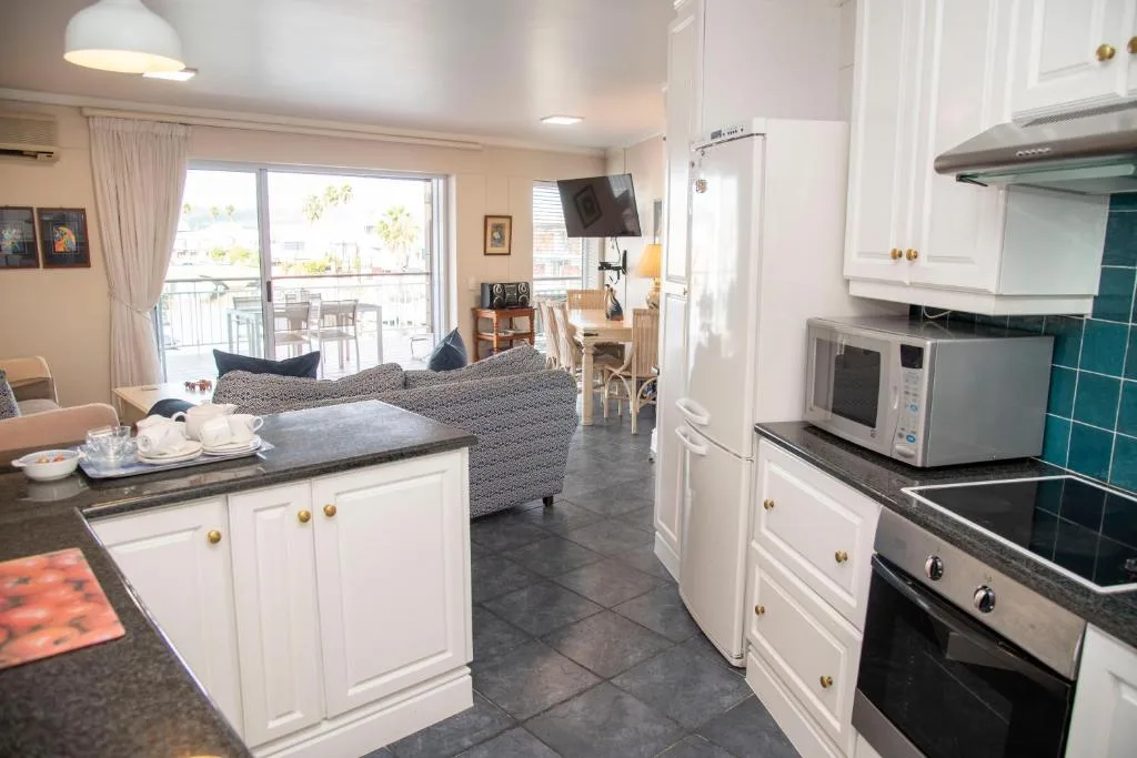 Modern kitchen with white cabinetry, stainless steel appliances, and open-plan living area