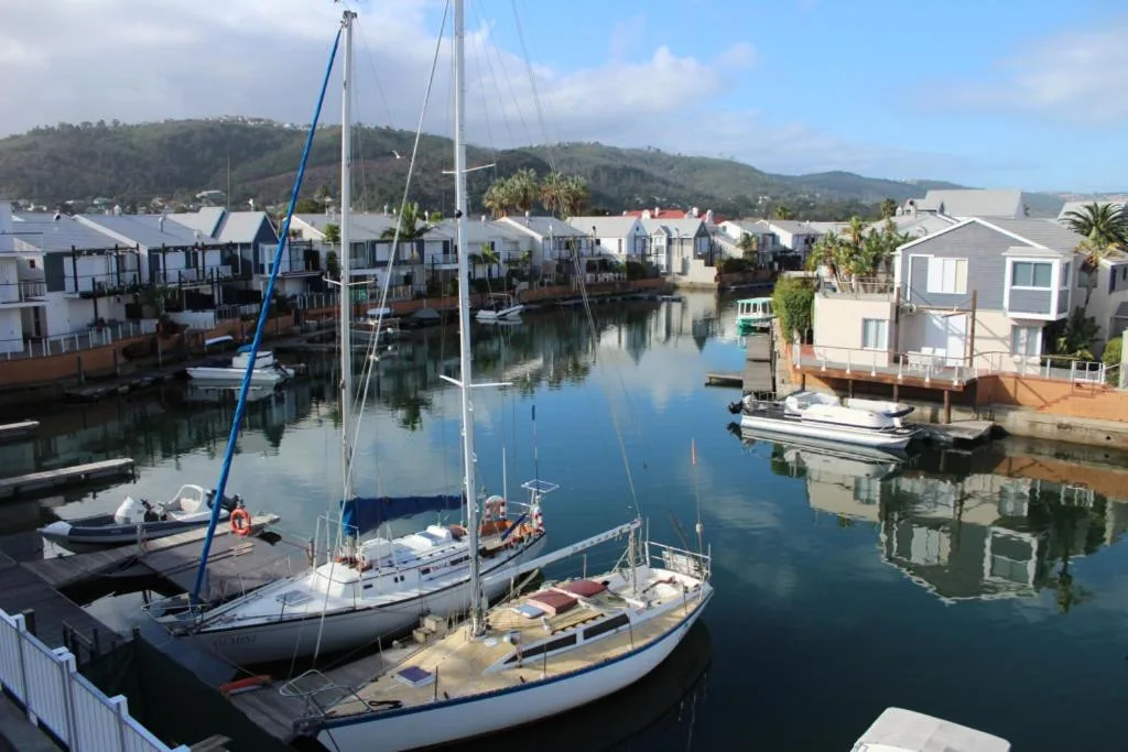 Scenic waterfront view of Knysna lagoon with sailboats and residential properties