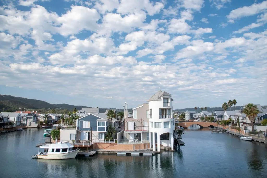 Waterfront property with lagoon views and moored boats under blue sky