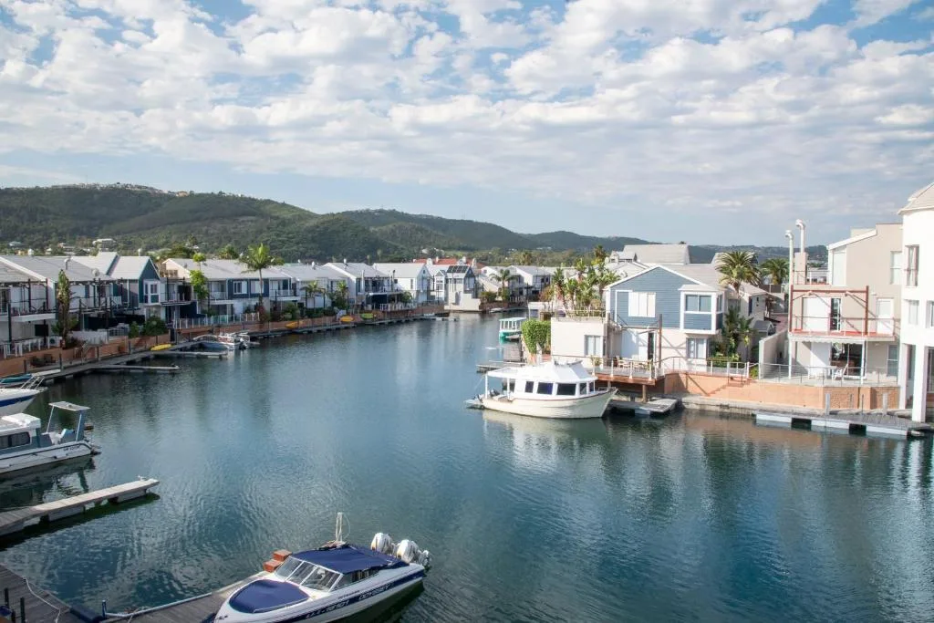 Scenic waterfront lagoon view with boats and tree-covered mountains