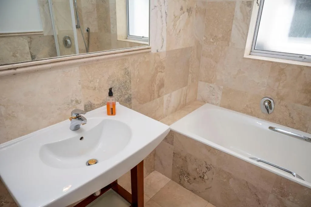 Spacious bathroom with double vanity sink and travertine tiling