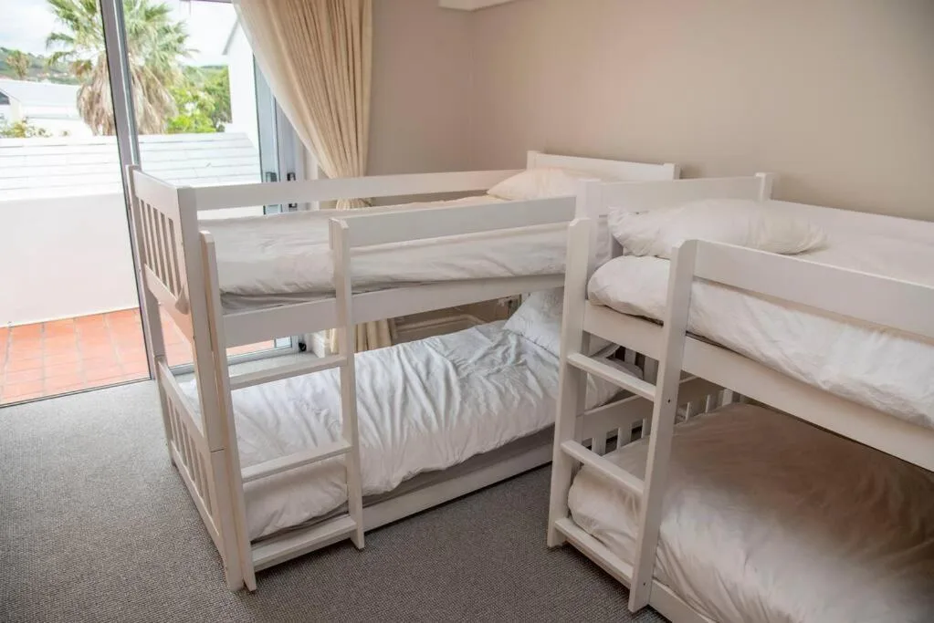 Bright bedroom with multiple white bunk beds and ocean view access