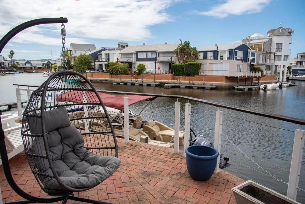 Waterfront deck with hanging chair overlooking lagoon and residential properties