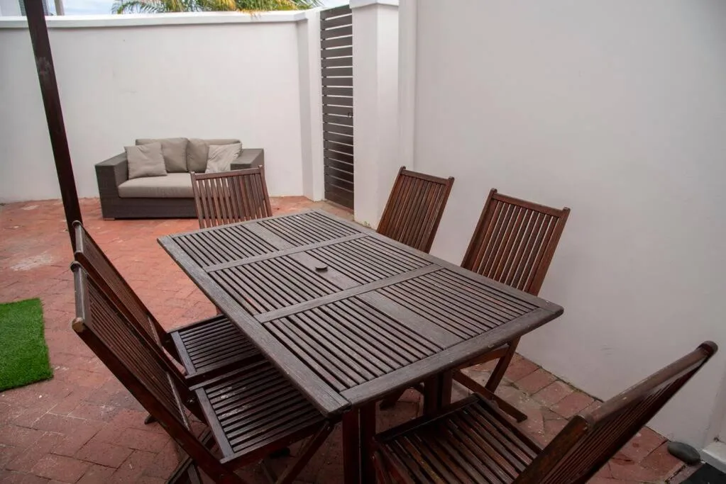 Outdoor patio with wooden dining table and seating area, lounge sofa visible