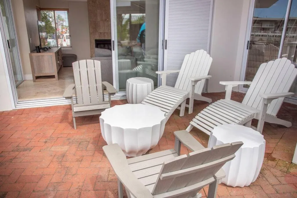 Outdoor patio with white Adirondack chairs and round tables on terracotta brick