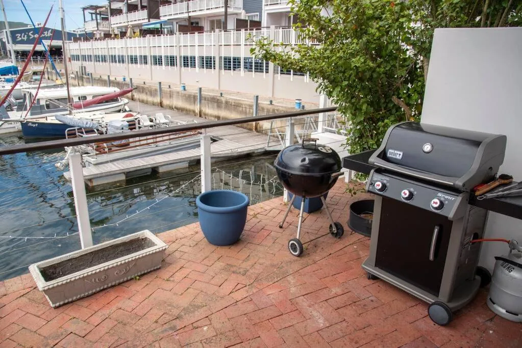 Waterfront patio with braai grills overlooking moored boats and harbor