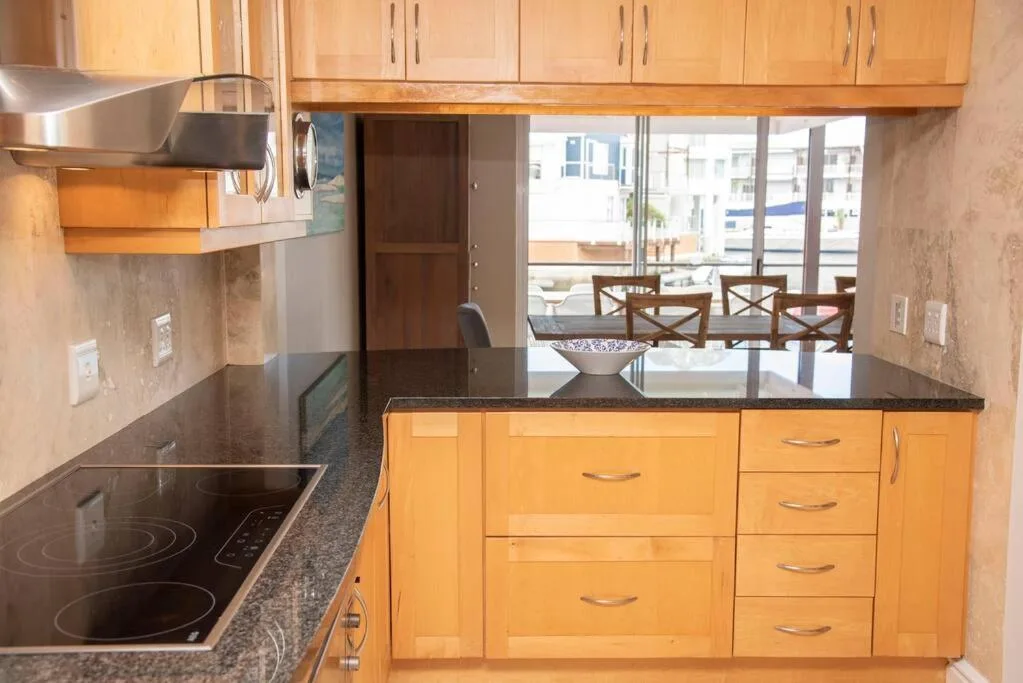 Modern kitchen with wooden cabinetry, dark countertops, and stainless steel appliances