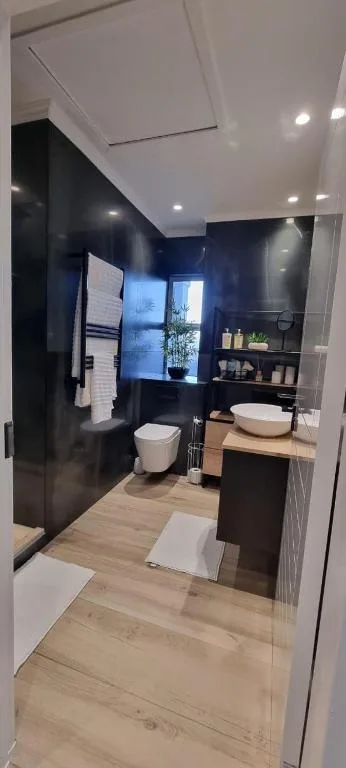 Modern bathroom with dark feature wall, vessel sink, and glass shower enclosure