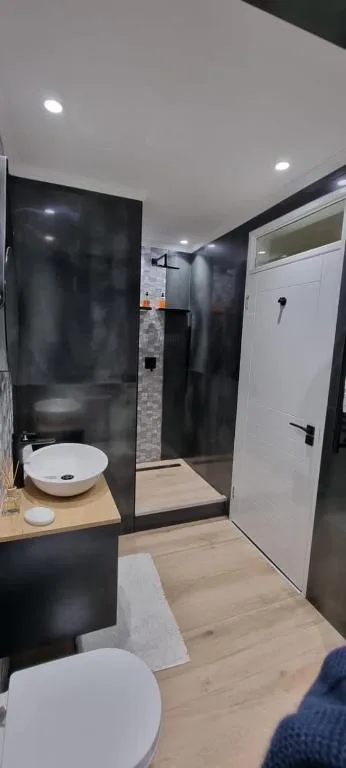 Modern bathroom with black shower enclosure and white round sink vanity