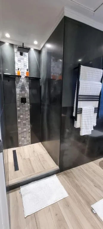 Modern bathroom with large black glass shower enclosure and heated towel rack