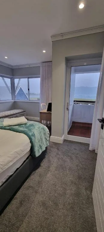 Bright bedroom with bed, large windows overlooking water views and canal scenery