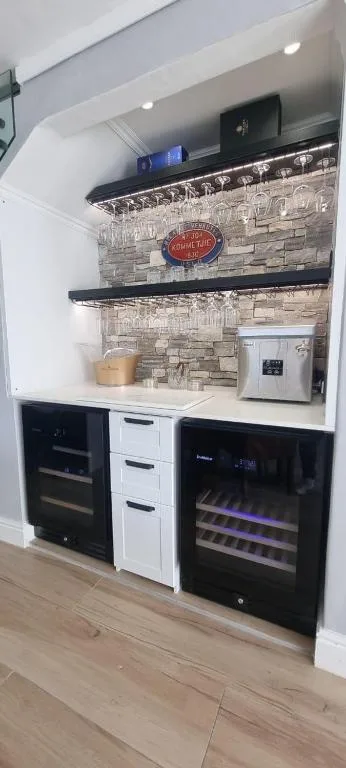 Modern kitchen nook with stone backsplash, built-in appliances, and wine fridge