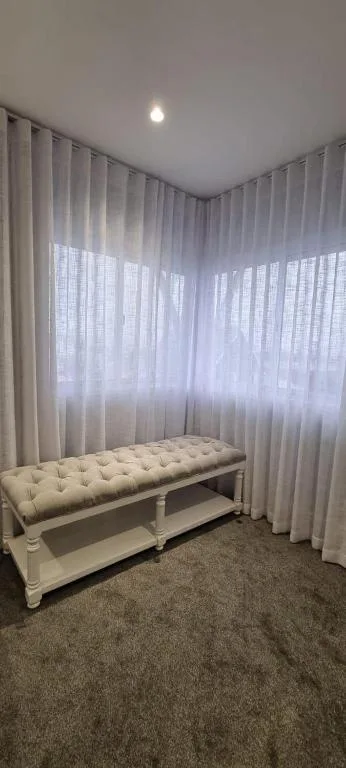 Elegant cream bedroom bench with tufted cushion and flowing white curtains