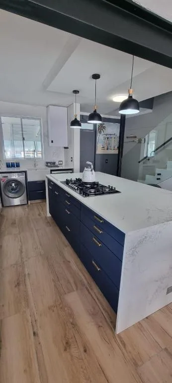 Modern kitchen with dark cabinetry, white countertop, and gas stovetop