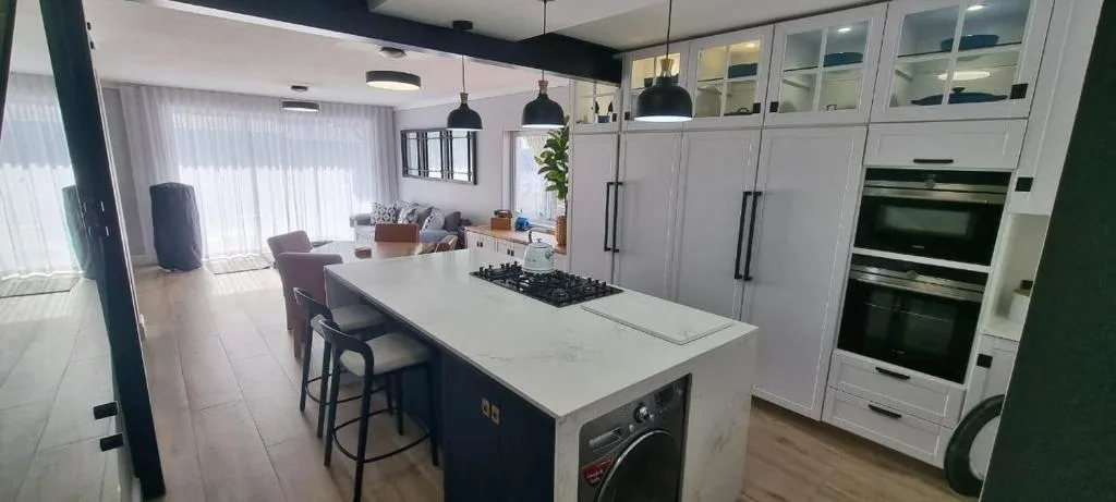 Modern open-plan kitchen with white cabinetry, island seating, and stainless steel appliances
