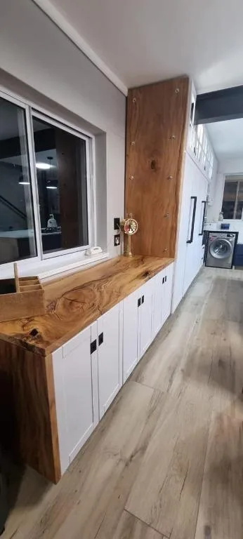 Modern kitchen with wooden countertop, white cabinetry, and window overlooking water
