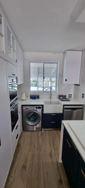Modern kitchen with washing machine, dishwasher, and window overlooking water