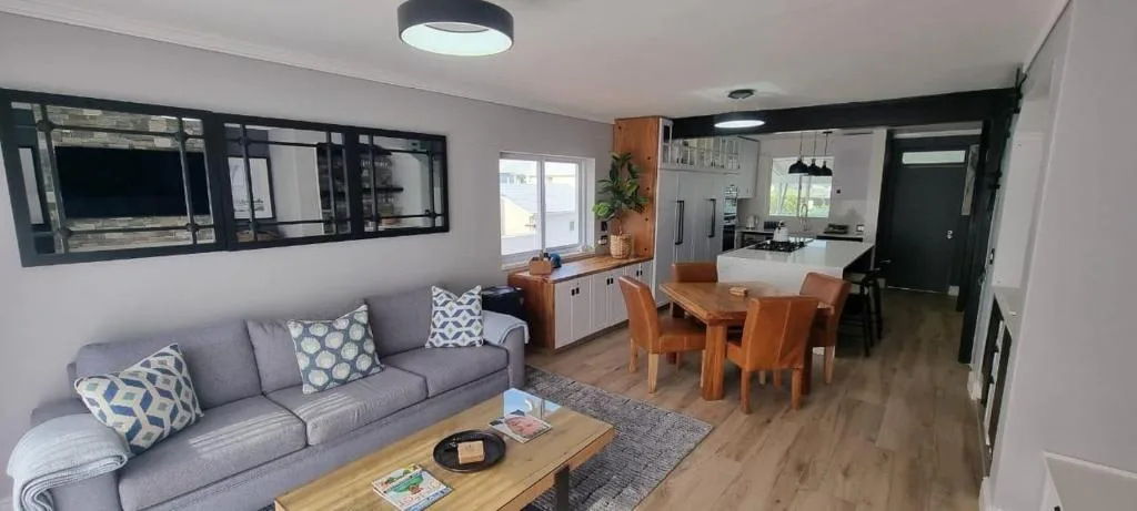 Open-plan lounge with grey sofa, wooden coffee table, and patterned cushions