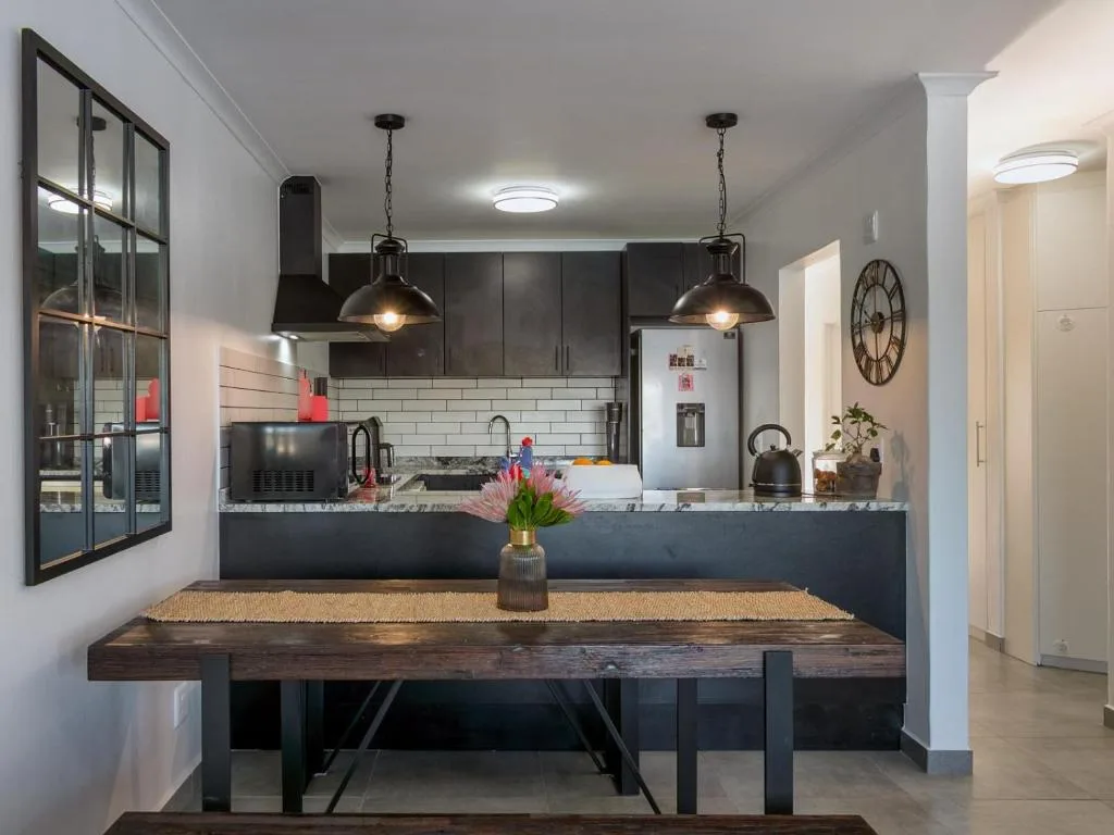 Modern open-plan kitchen with dark cabinetry, pendant lights, and dining table