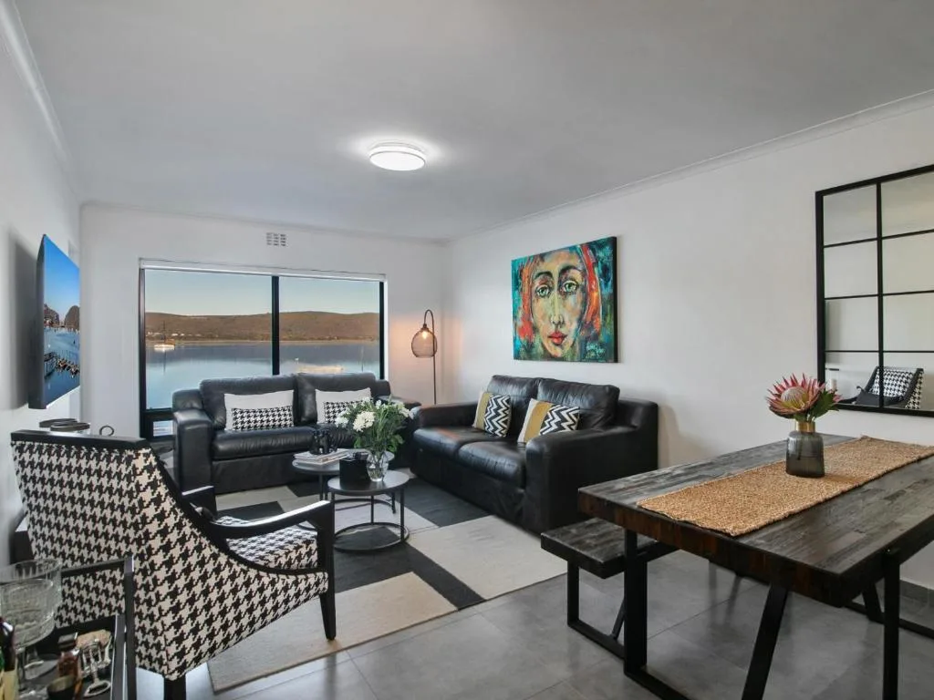 Modern lounge with black leather sofas and lagoon view through large windows