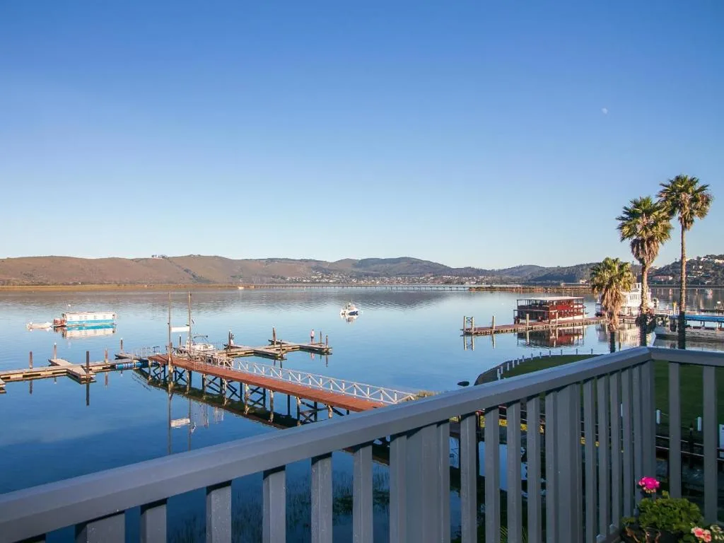 Serene lagoon view with moored boats, palm trees, and distant mountains