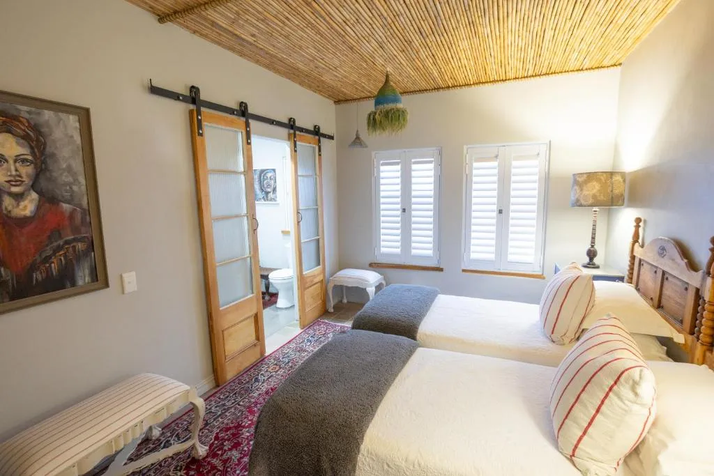 Spacious bedroom with two beds, wooden sliding doors, and shuttered windows
