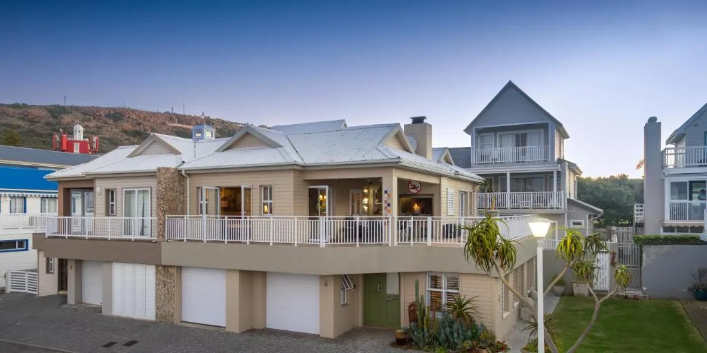 Beige coastal home with wraparound deck and garage, hillside setting